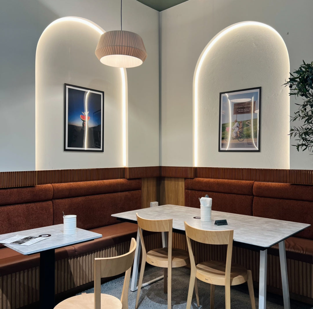 Modern restaurant interior with curved LED strip arch, brown booths, wooden chairs, and tables.