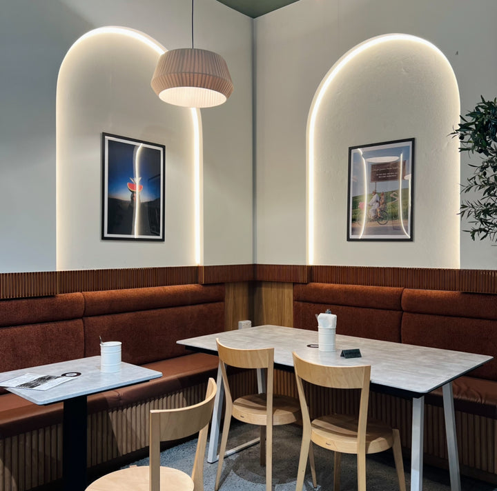 Modern restaurant interior with curved LED strip arch, brown booths, wooden chairs, and tables.