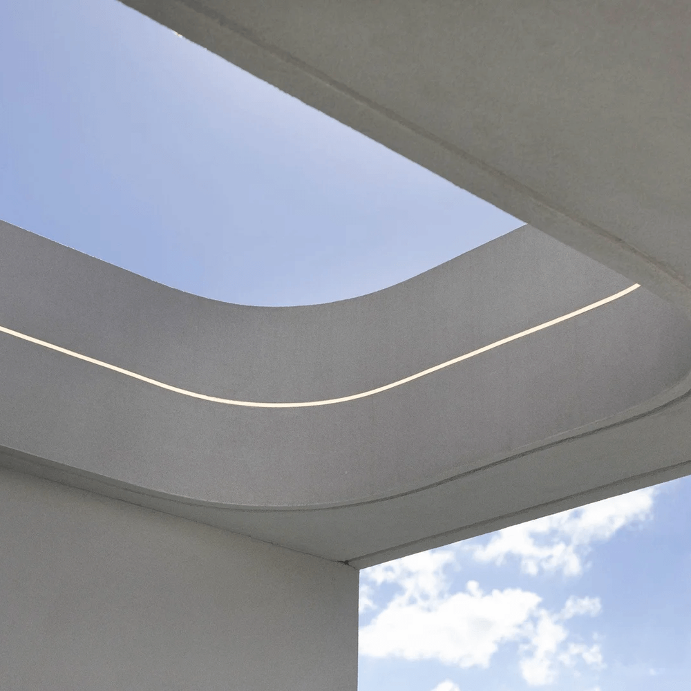 Modern architectural detail with curved concrete surface and blue sky.