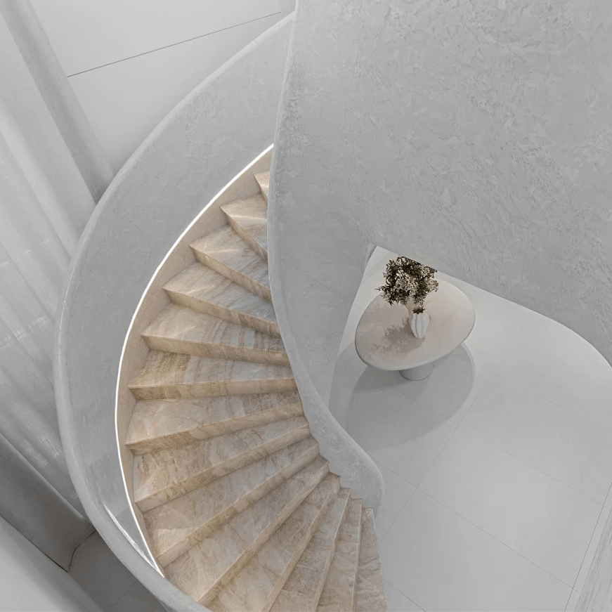 Spiral staircase with a small round table and plant in a minimalistic setting